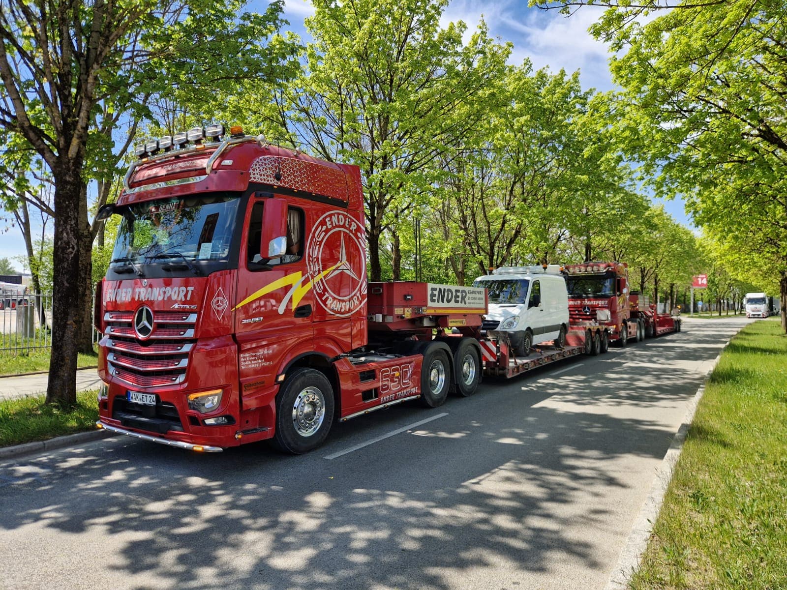 Roter Ender-Tieflader mit Bagger auf einer Allee