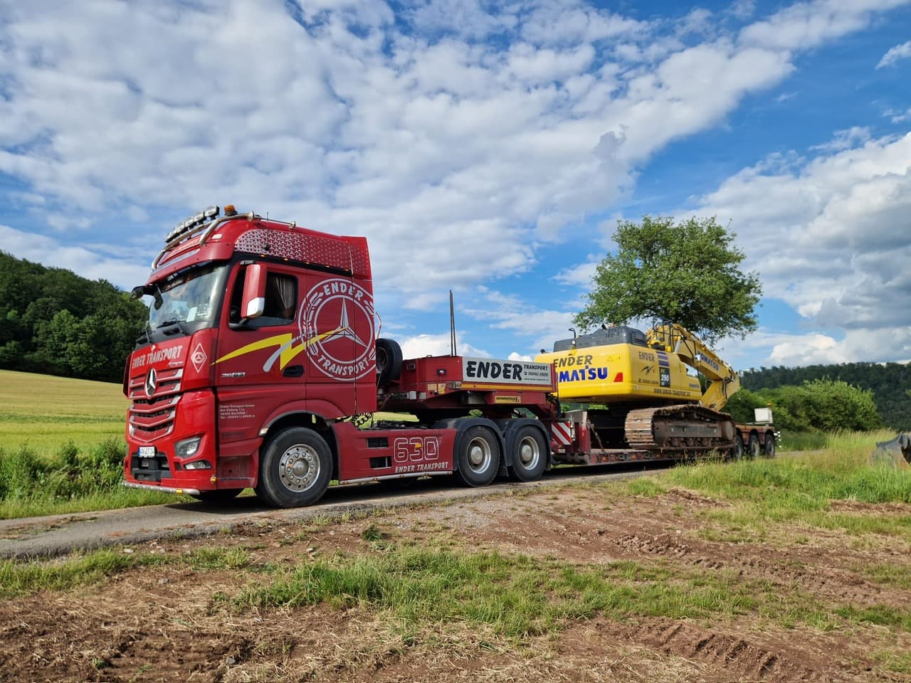 Ender-Tieflader mit Bagger an einer Baustelle