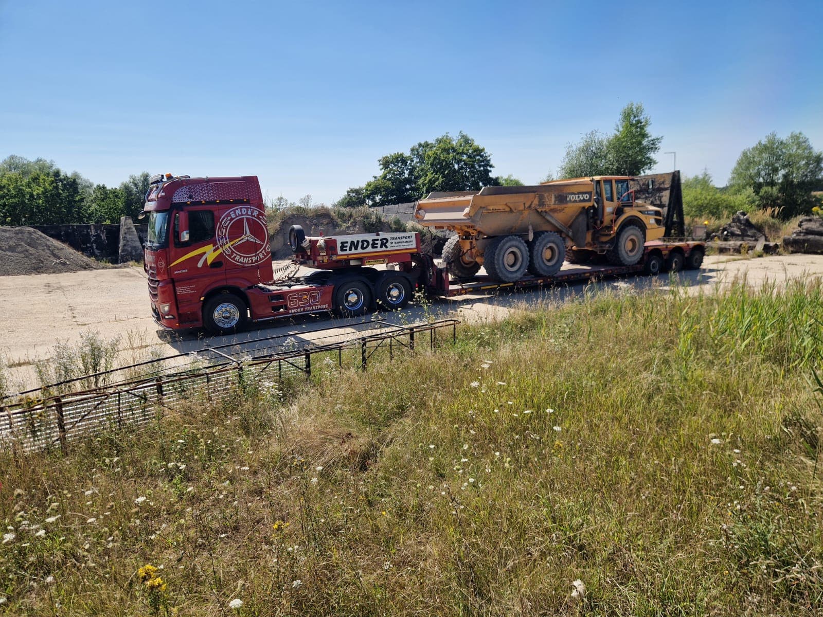 Ender-Tieflader beim Transport eines großen Dumpers