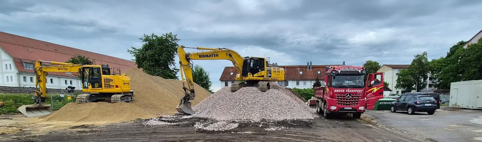 Ender-Baumaschinen und Kipper gemeinsam auf einer Baustelle
